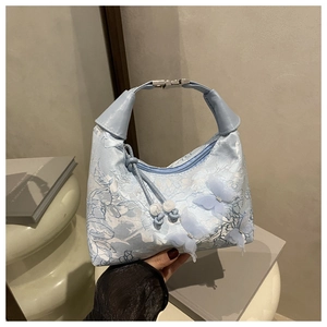 Close-up of light blue lace bag featuring 3D butterfly appliques and silver metal clasp