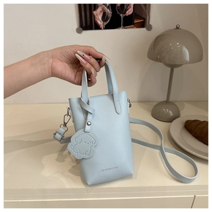 Detail of light blue mini leather crossbody bag with a cute dog charm and silver hardware