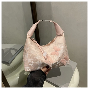 Close-up of pink hobo bag featuring floral embroidery and 3D butterfly details