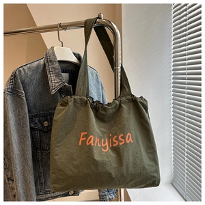 Detail of dark army green canvas tote bag with orange Fanyissa lettering and pleated top