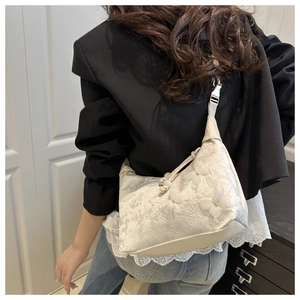 Detail of off-white lace shoulder bag featuring 3D butterfly embroidery and floral patterns