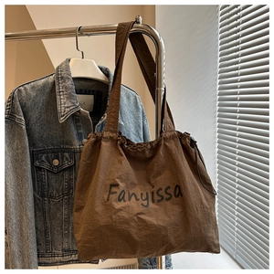 Detail of dark brown nylon tote bag with textured fabric and Fanyissa lettering on a hanger