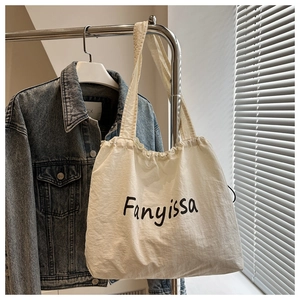 Detail of drawstring canvas shoulder bag showing Fanyissa lettering and pleated texture