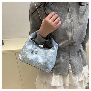 Close-up of light blue lace handbag with intricate white floral embroidery and bead drawstring