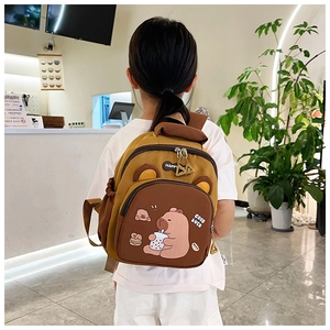 Detalle de niño con mochila de colores en contraste y estampado de oso en una cafetería
