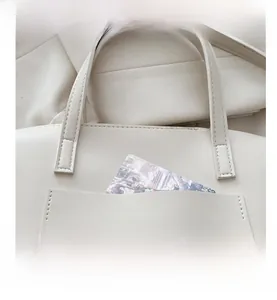 Detailed close-up of cream leather tote bag featuring a front pocket with decorative card