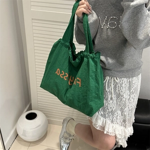 Green nylon tote bag with orange letters and adjustable drawstring for casual daily use