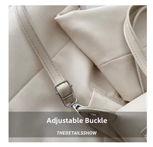Detail of adjustable silver buckle and spring hook on cream canvas shoulder bag strap