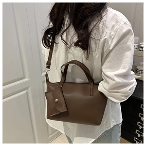 Detail of vintage brown faux leather bucket bag with mini decorative pouch and shoulder strap