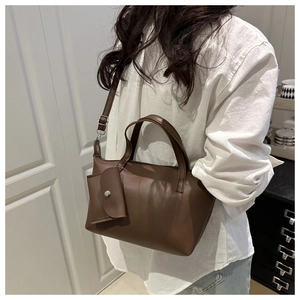 Detail of dark brown leather tote bag with a mini detachable pouch worn by a model