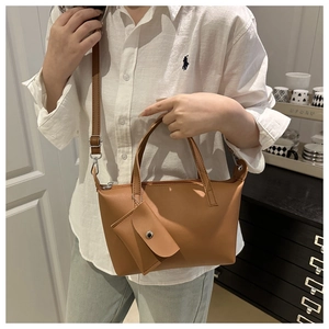 Close-up of brown leather tote bag with detachable strap and small coin purse detail