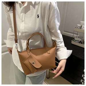 Detail of a brown leather tote bag with a small envelope charm and long shoulder strap