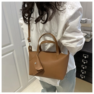 Detail of a brown leather bucket bag with a detachable strap and matching charm purse