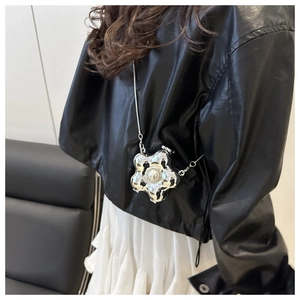 Detail der silbernen Blumen-Minitasche mit Perle und Kette auf einer schwarzen Lederjacke