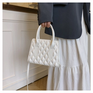 Close-up of white quilted handbag featuring elegant diamond stitching and crossbody strap