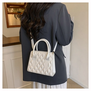 Rear view of a model styling a white quilted crossbody bag with top handles and strap