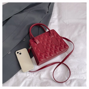 Detail view of red quilted leather handbag with dual handles and detachable shoulder strap
