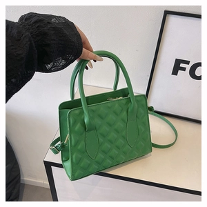 Detail of green quilted crossbody bag with textured leather and gold-toned metal hardware