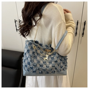 Detail of blue and white checkered tote bag featuring gold chain and deer charm pendant