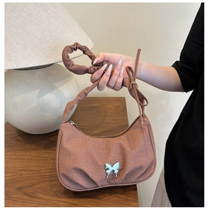 Détail de la texture en tissu plissé marron et boucle papillon bleu clair sur le sac à main