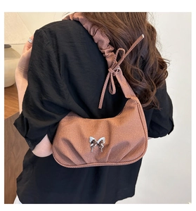 Détail d'un sac porté épaule marron caramel avec boucle papillon argentée et bandoulière