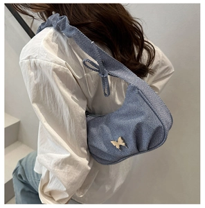 Detail of blue denim hobo bag with silver butterfly buckle and pleated shoulder strap