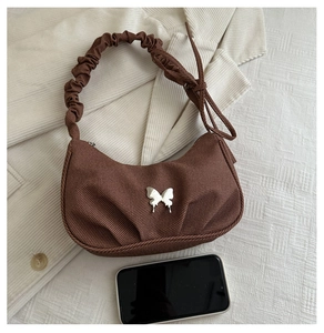 Détail du sac croissant en velours côtelé marron avec papillon argenté et anse froncée