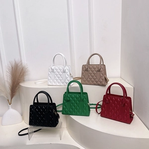 Five quilted faux leather handbags in various colors arranged on a white tiered display