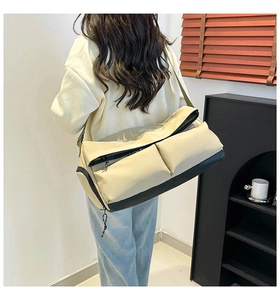 Detailed back view of a large cream and black waterproof sports bag worn by a model