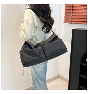 Rear view of a large black nylon crossbody bag with wide strap and multiple pockets