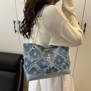 Blue star pattern tote bag with gold chain strap shown on model in a modern room