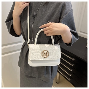 Détail du sac à main blanc avec rabat tressé et boucle dorée M porté par un mannequin