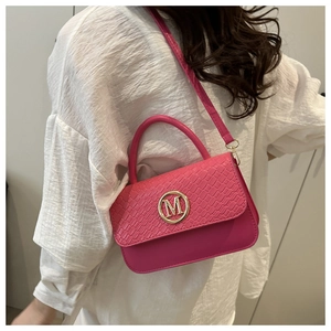 Détail du sac à main rose fuchsia à motif crocodile avec boucle M dorée sur le mannequin
