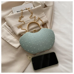 Detail of mint green textured fabric box bag with gold metal handle and crystal clasp