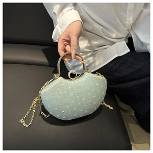 Detail of light blue textured chain bag with a gold metal handle and rhinestone ring buckle