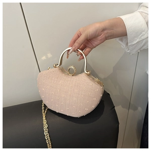 Close-up of beige evening box bag with gold metal handle and sparkling diamond clasp