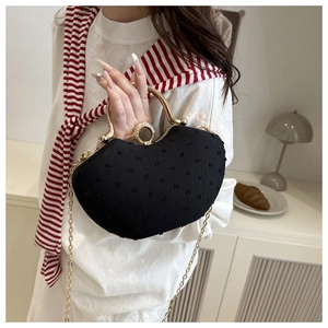 Detail of black evening clutch bag with rhinestone ring clasp and gold metal handle