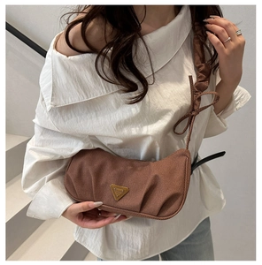 Detail of brown corduroy shoulder bag with pleated scrunchie strap and gold triangle logo