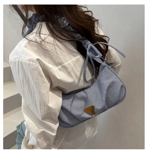 Close-up of blue striped canvas bag with triangle logo and pleated bow shoulder strap