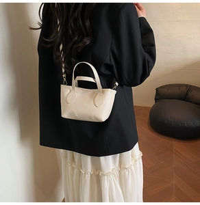 Detail of off-white lychee textured bucket bag with gold hardware and fine stitching