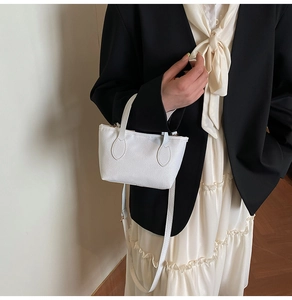 Detail of white litchi pattern leather bucket bag with an adjustable crossbody strap