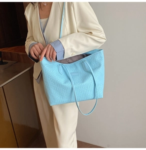 Detailed close-up of light blue woven tote bag showing texture and slim shoulder straps