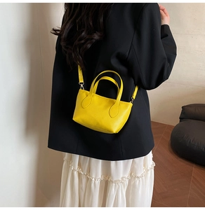 Detail of a bright yellow pebbled leather mini tote bag with gold hardware and shoulder strap
