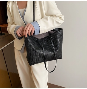 Detailed view of black woven tote bag texture and slender shoulder straps for women