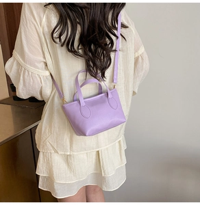 Close-up of a lavender mini bucket bag with litchi grain texture and thin shoulder strap