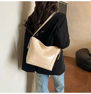 Minimalist beige leather bucket bag shown from behind to display size and fit on a model