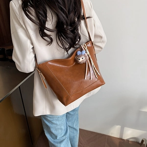 Women's brown PU leather tote bag with a cute bear charm, perfect for daily commuting