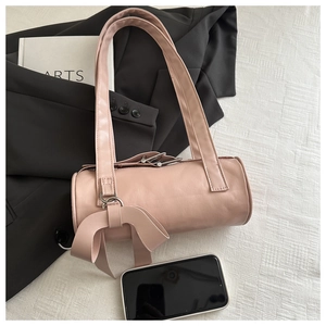 Detail of light pink cylinder shoulder bag featuring a large decorative leather bow