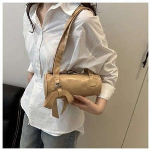 Detail of khaki cylindrical underarm bag with a large decorative bow on the side