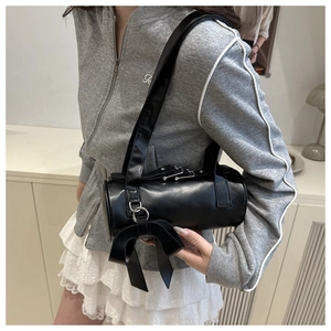 Close-up of black cylinder shoulder bag featuring large bow detail and matte leather finish